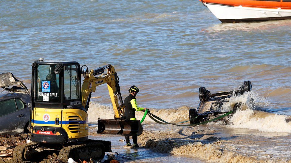 Rescue team members attempt to remove a car from the sea