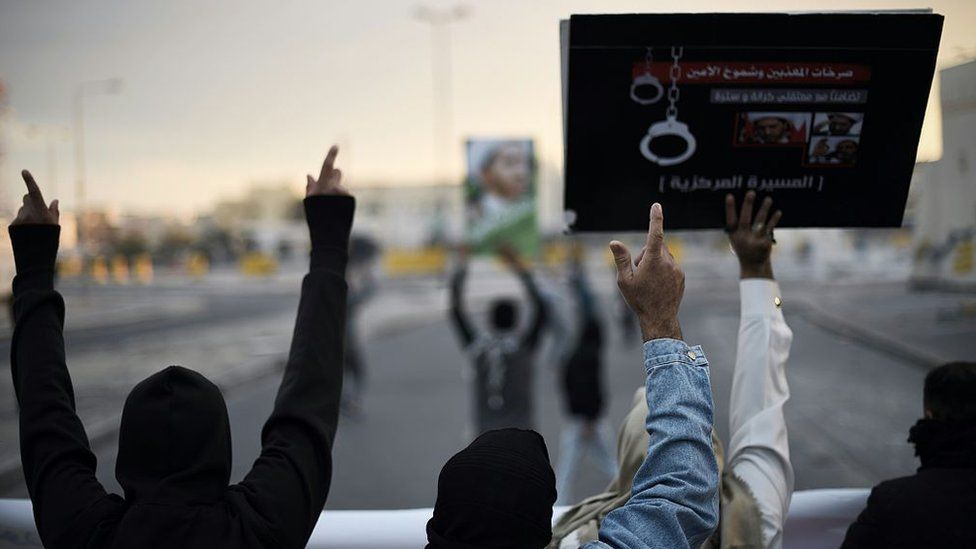 Bahraini protestors hold up placards depicting portraits of Sheikh Ali Salman, leader of Wefaq, during clashes with riot police in Sitra (29 January 2016)