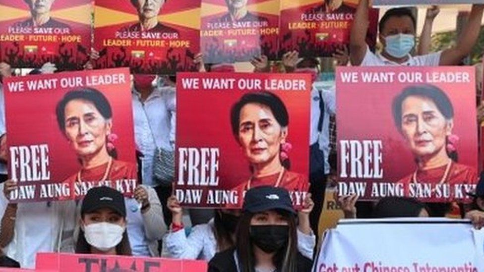 Protesters in Myanmar hold up signs showing jailed leader Aung San Suu Kyi