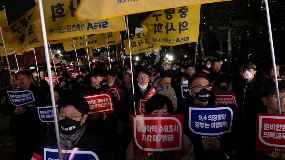 Doctor protesters shout slogans and carry signs reading 'Opposition to the increase in medical schools' during a protest against the government's medical policy in Seoul