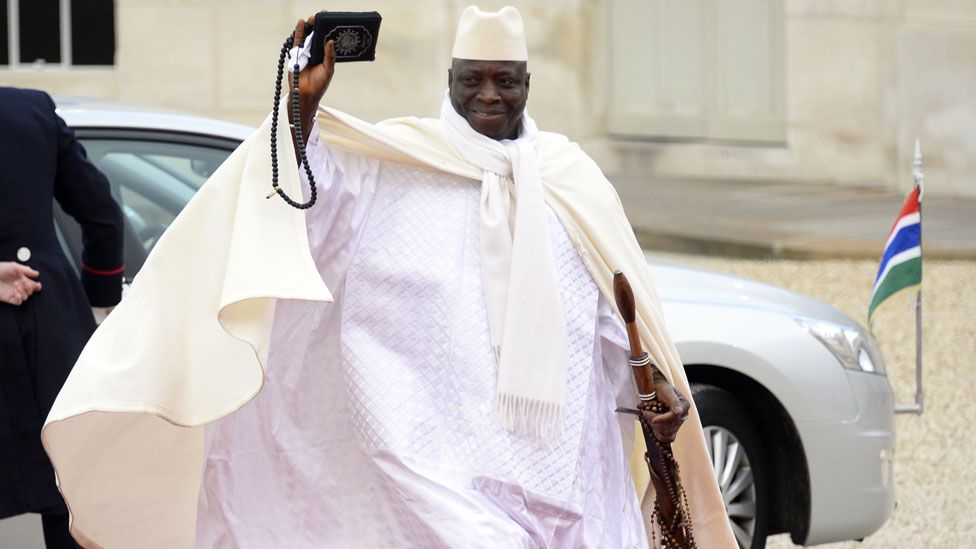 Yahya Jammeh waves as he walks on a red carpet