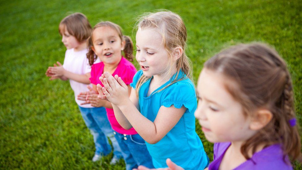 Stock image of four little girls clapping