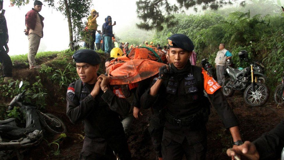 Indonesian police carry the body of a Mount Marapi eruption victim on Tuesday