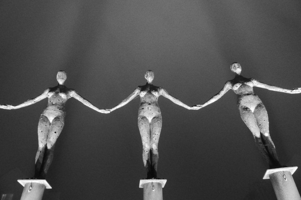 A row of rusted female statues