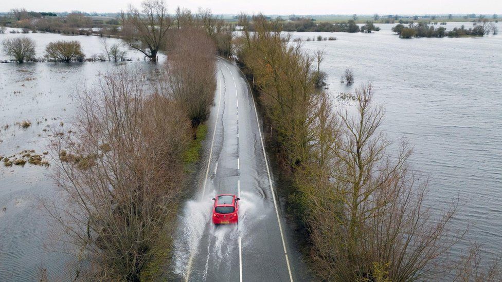 Cars make their way through surface water on the A1101 in Welney in Norfolk, where the River Delph and New Bedford River have flooded the surrounding area