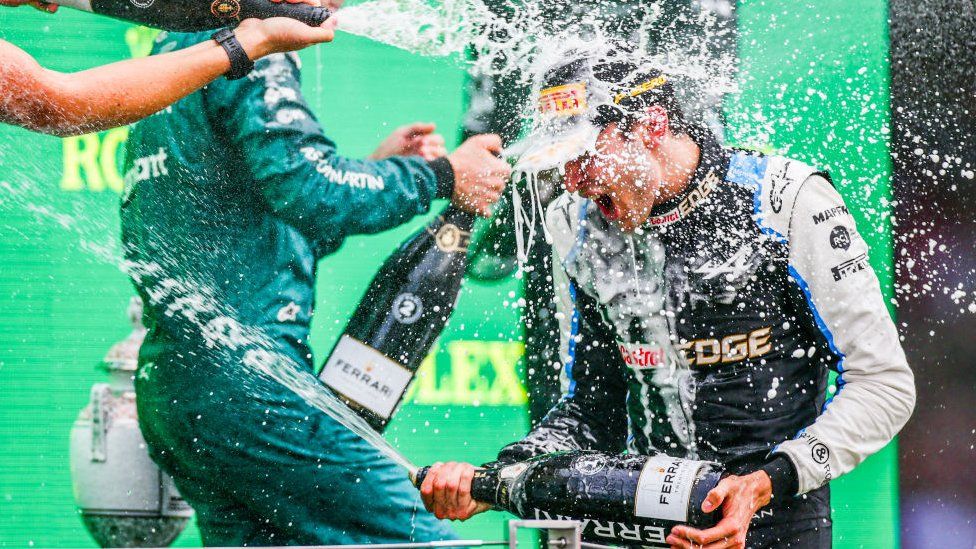 Esteban Ocon is sprayed with champagne on the podium.