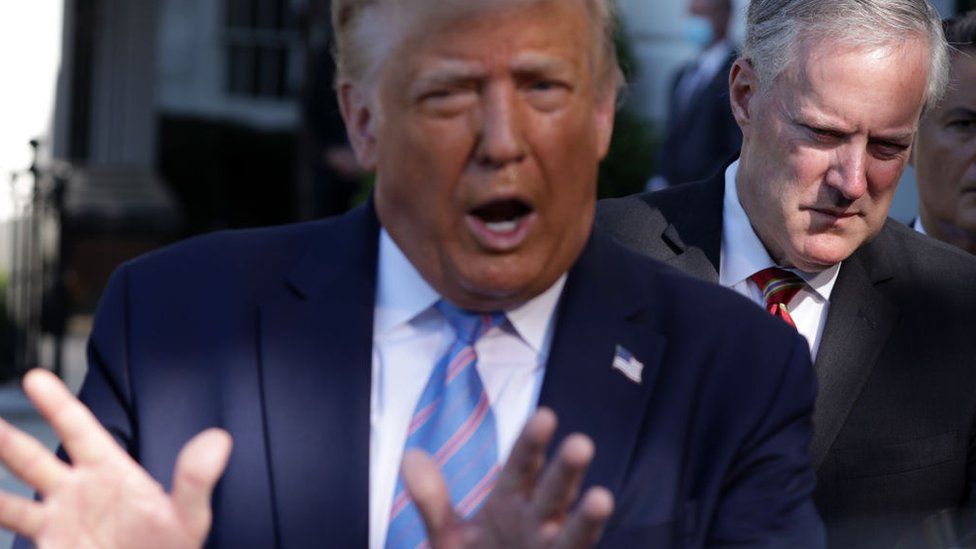 Donald Trump speaks as White House Chief of Staff Mark Meadows (R) listens at the White House on 29 July 2020