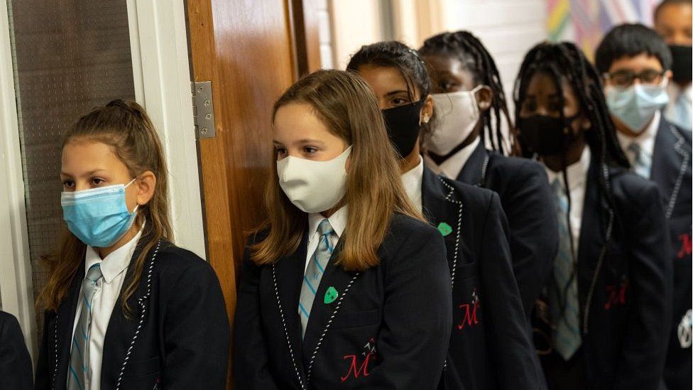 school children queuing wearing masks