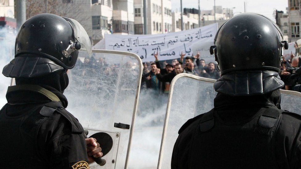 Palestinian policemen stand opposite demonstrators during a protest against a decision by the Palestinian Authority to grant public land to the Russian church, in the West Bank city of Hebron, on 4 February 2017