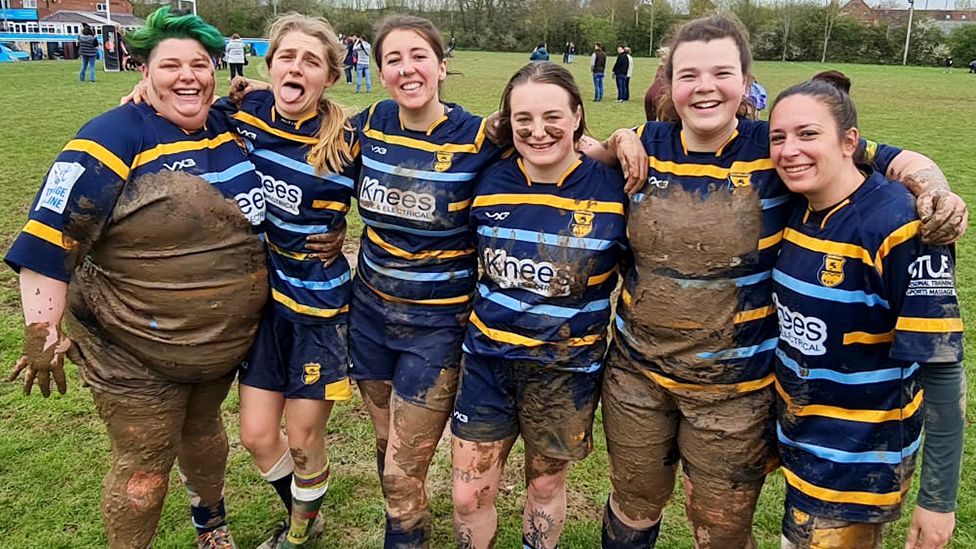 A women's rugby team covered in mud