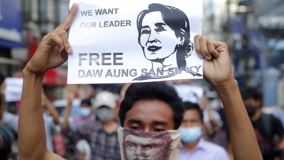 A civilian at a protest in the aftermath of the coup with a sign reading "Free Aung Sun Suu Kyi"
