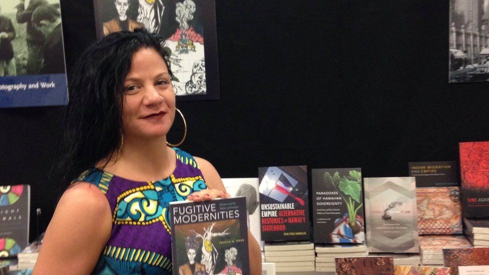 Jessica Krug poses with her book Fugitive Modernities in 2019