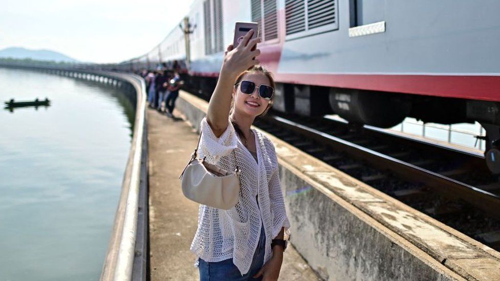 This photograph taken on November 4, 2023 shows a tourist travelling aboard the popular "Floating train" taking a selfie along the railway tracks during a stop in the middle of Pasak Jolasid Dam, Thailand's biggest reservoir in Lopburi province.