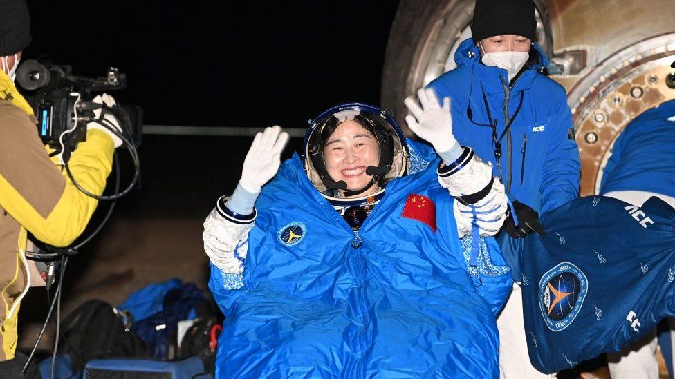 Chinese astronaut Liu Yang waving as officials assist her from the capsule of the Shenzhou-14 spacecraft after landing in China's Inner Mongolia