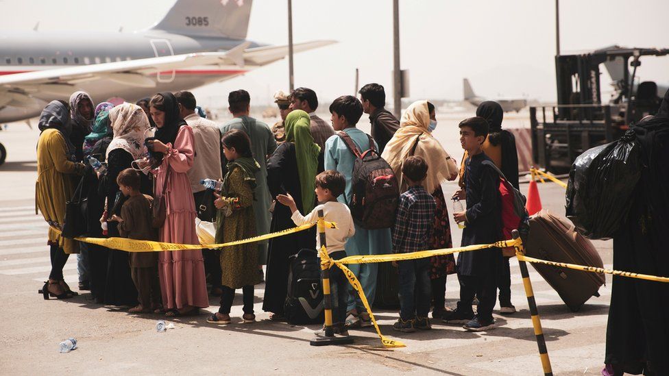 Civilians prepare to board a plane during an evacuation at Hamid Karzai International Airport, Kabul