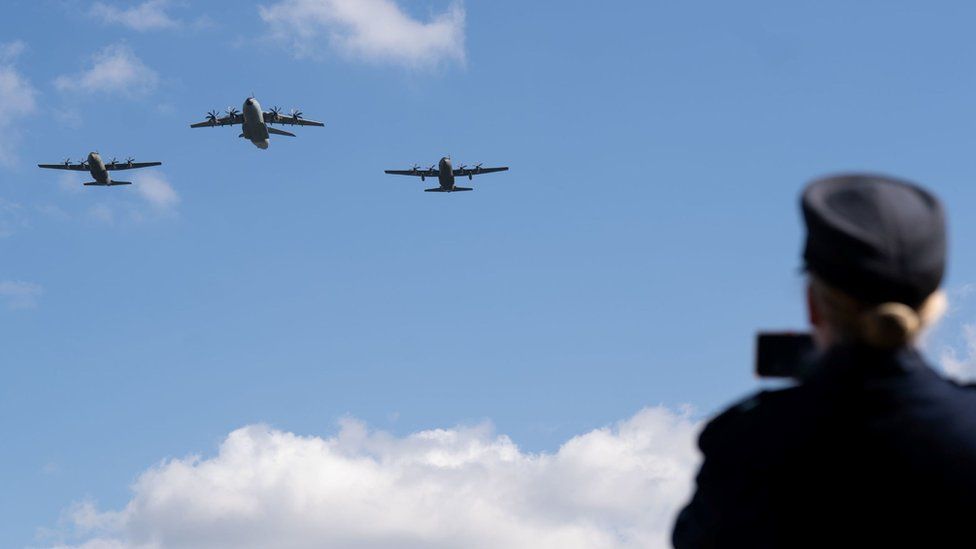 The flypast rehearsal with three planes against a blue sky being watched by people on the ground