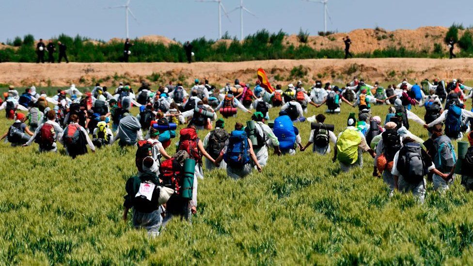 Activists running through fields with backpacks