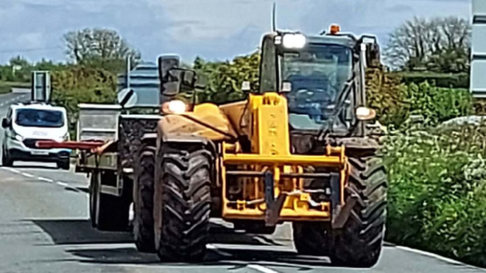 the tractor with its overhanging load sticking out from the trailer