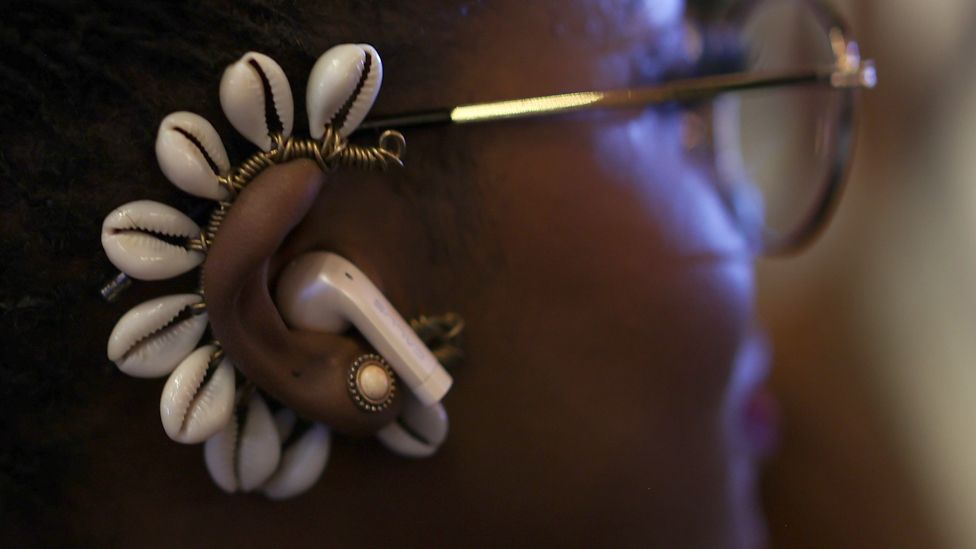 A model wear a shell ear jewellery and earbuds in Dakar, Senegal - Saturday 9 December 2023