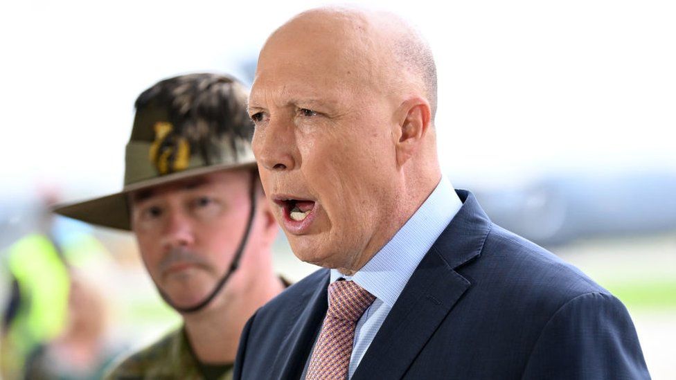 Peter Dutton speaks in front of a defence force member