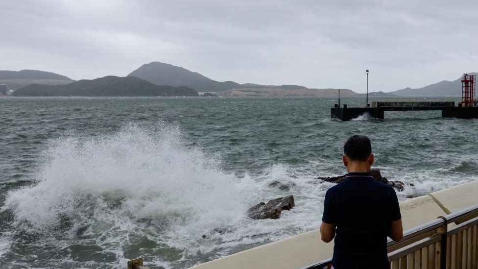 A man watches the waves at the seaside as Typhoon Talim approaches, in Hong Kong, China, July 17, 2023.