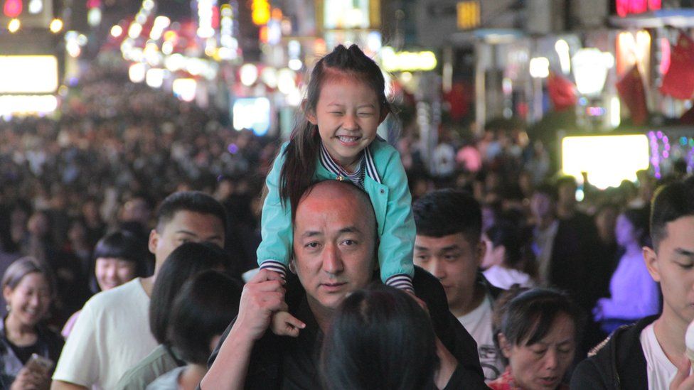 A girl rides on her father's neck at Taidong Pedestrian Street in Qingdao, Shandong, 5 October 2018