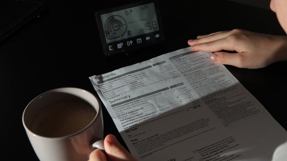 An energy bill being read next to a smart meter