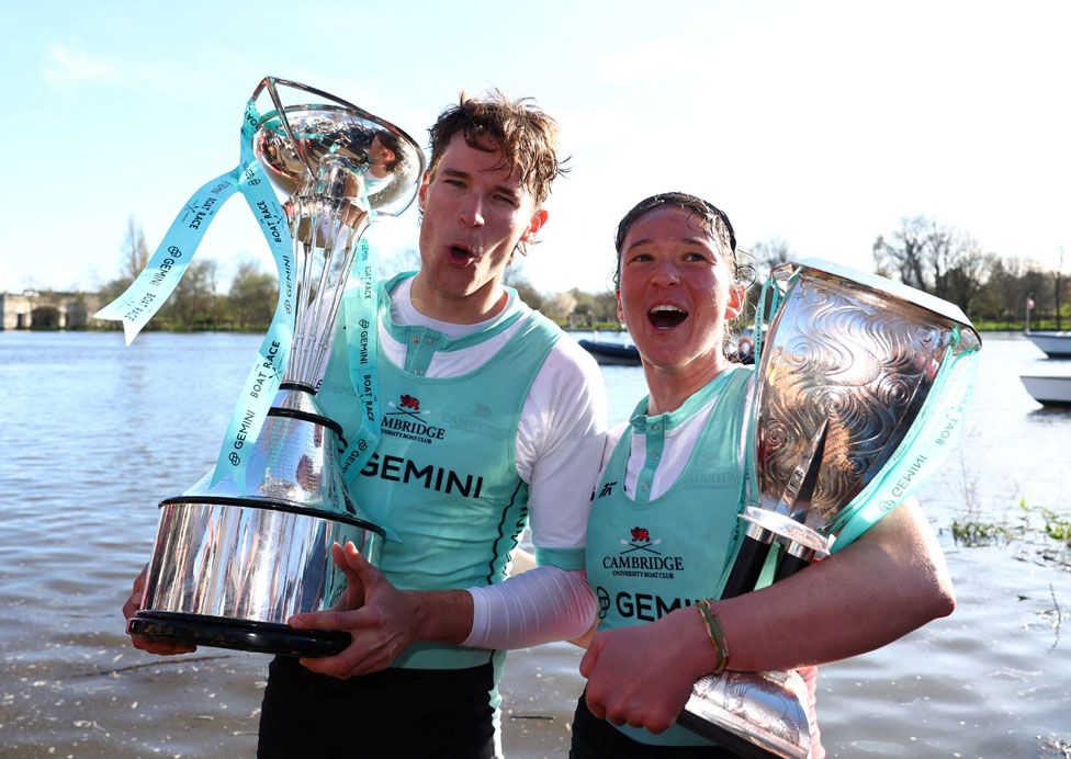 Cambridge's Augustus John and Jenna Armstrong celebrate with the trophies after winning the men's and women's races on the River Thames London, England.
