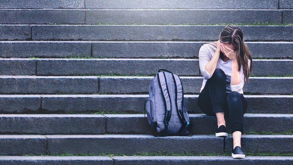 Distressed young woman with rucksack on steps (file image)
