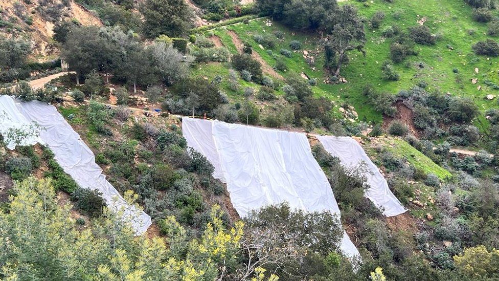 Plastic sheets cover a hillside in California which slid away for the first time this week