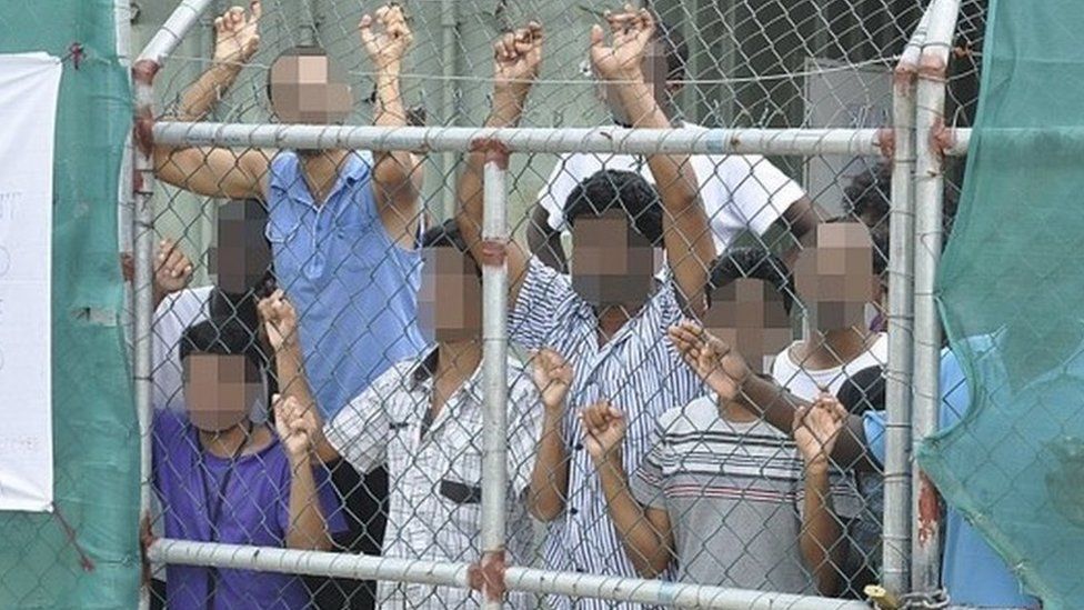 Asylum seekers look through a fence at the Manus Island detention centre in Papua New Guinea in 2014