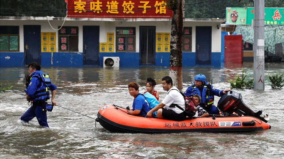 Rescue workers evacuate people through floodwaters with a boat in Zhuozhou, Hebei province, China