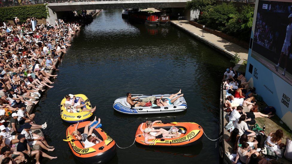 Les gens regardent la finale masculine de Wimbledon sur un écran à côté du Regent's Canal à Londres