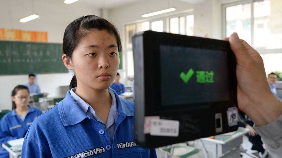 A teacher uses a machine which employs both fingerprint and facial recognition technology to check the identification of a student before a simulated college entrance exam