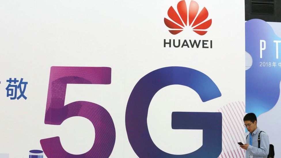 A man walking past a Huawei 5G sign