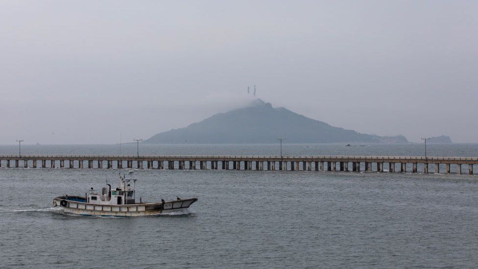 A fishing boats sails past a bridge on Yeonpyeong Island, South Korea, on Friday, June 26, 2020.