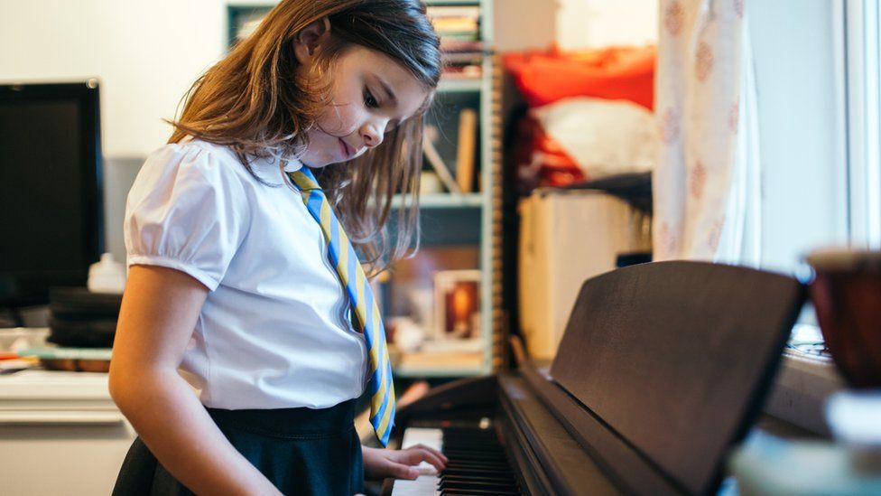 Young girl in school uniform playing keyboard