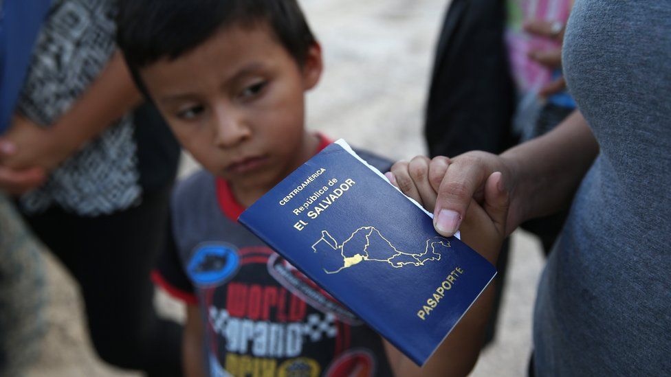 A boy stands near a El Salvador passport