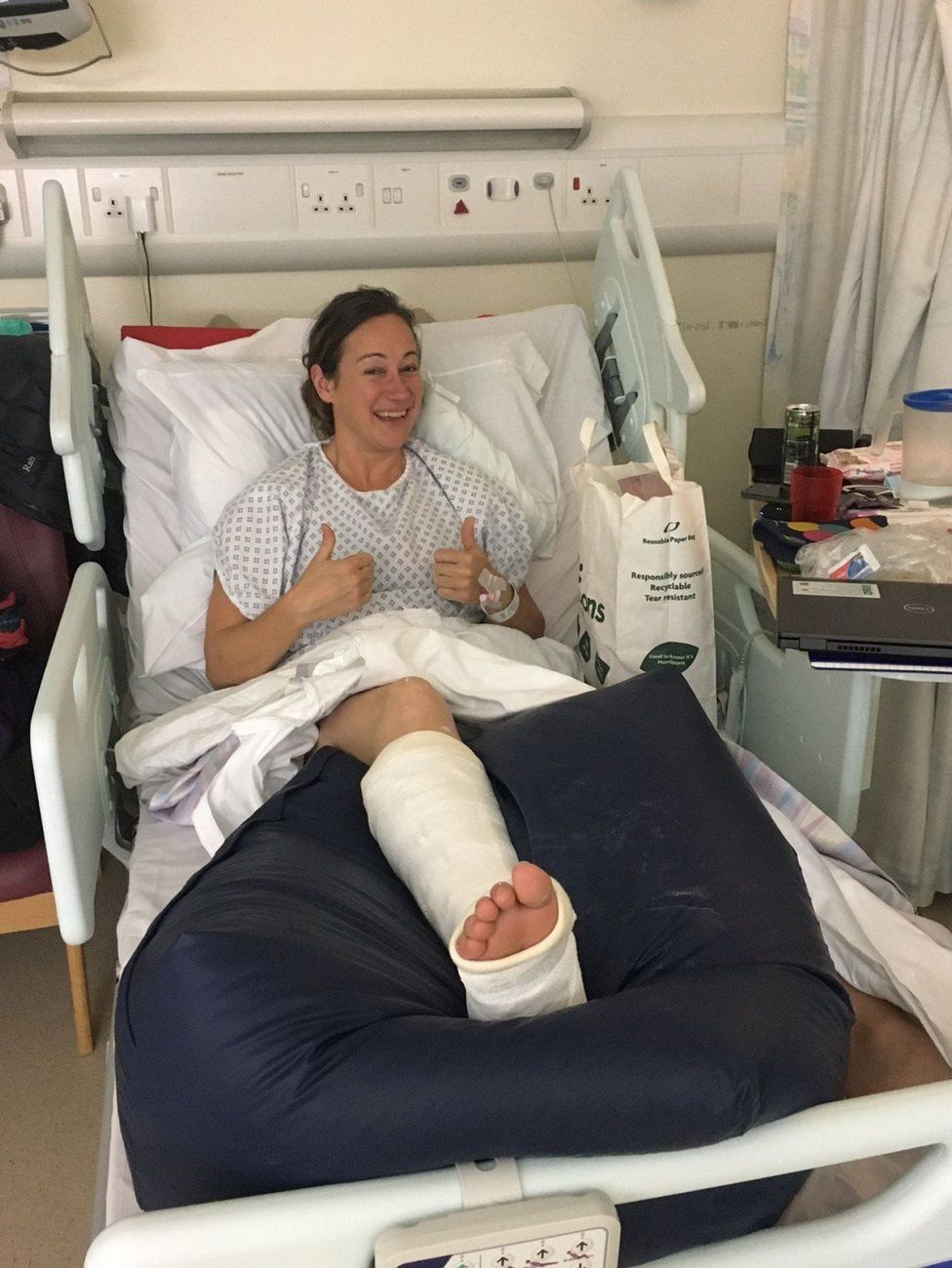 Claire Hughes giving a "thumbs-up" signal from her hospital bed