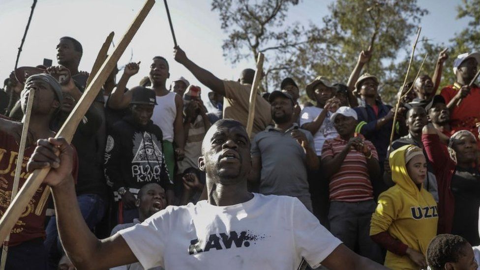 Zulu residents of the Jeppe Men Hostel scream waving batons in the Johannesburg CBD on September 3, 2019