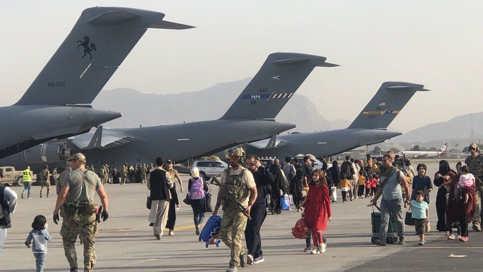 People on the tarmac at Kabul airport walking to C-17 aircraft to board flights to
