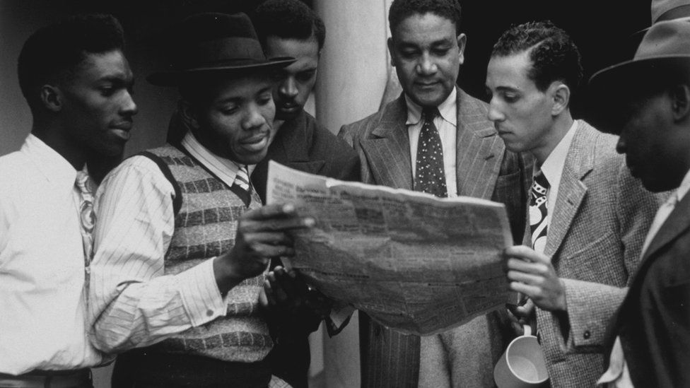 Jamaicans reading a newspaper whilst on board the Empire Windrush