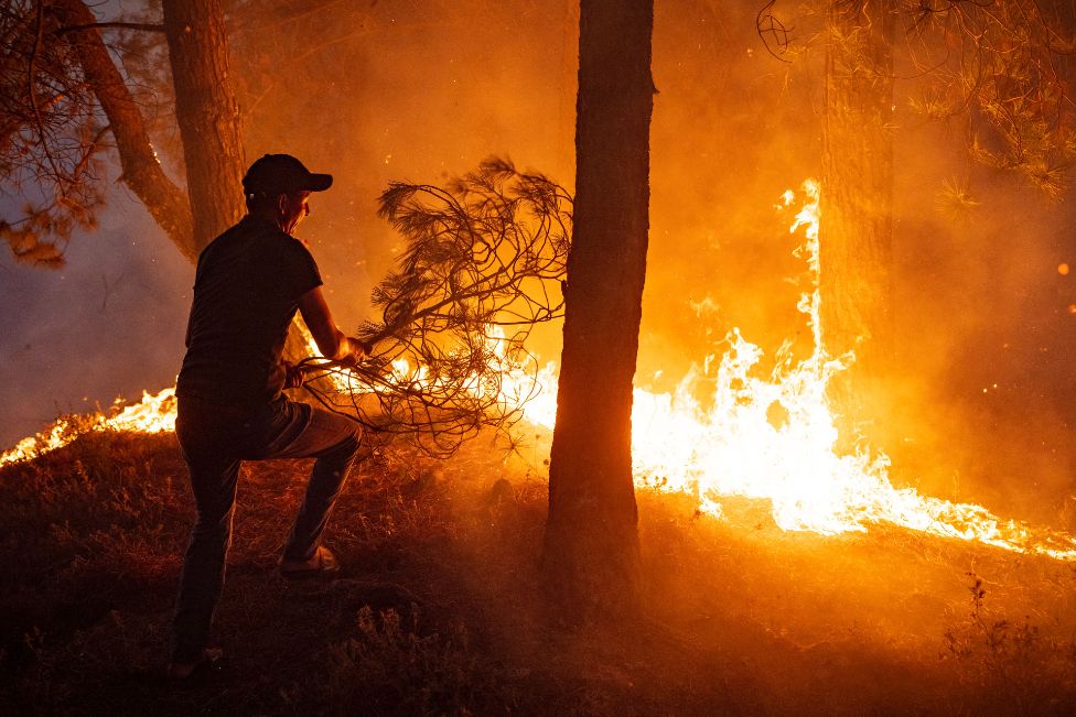 A Moroccan tries to help put out a fire as wild blazes destroyed some 200 hectares (500 acres) of forest in the region of Chefchaouen in northern Morocco on August 15, 2021