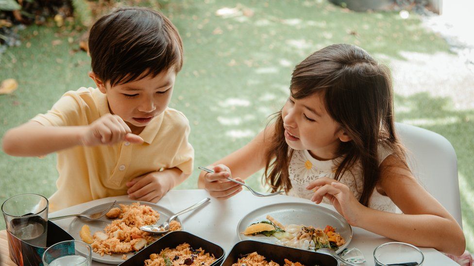 Stock image of children eating lab grown meat.