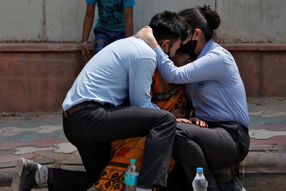 A woman is consoled by her children after her husband died due to the coronavirus disease (COVID-19) outside a mortuary of a COVID-19 hospital in New Delhi, India, April 15, 2021. REUTERS/Danish Siddiqui