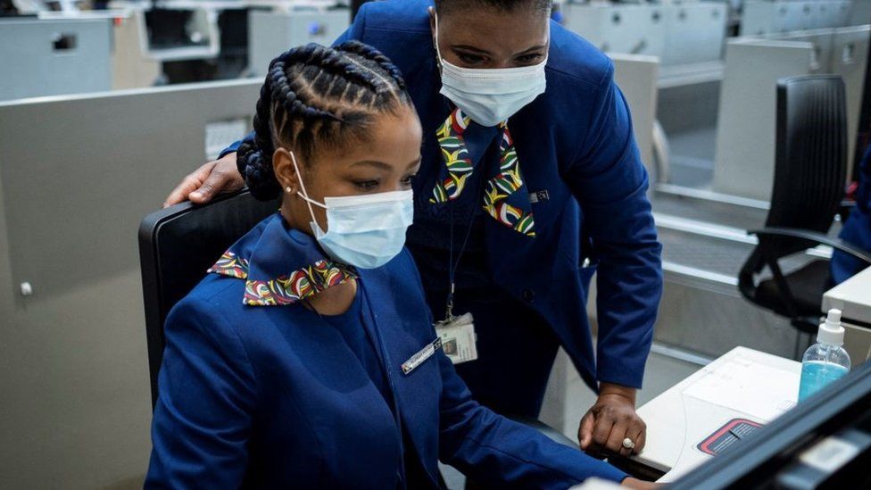 Сотрудники South African Airways (SAA) регистрируют пассажира (не видно) в O.R. Международный аэропорт Тамбо в Йоханнесбурге 23 сентября 2021 г.