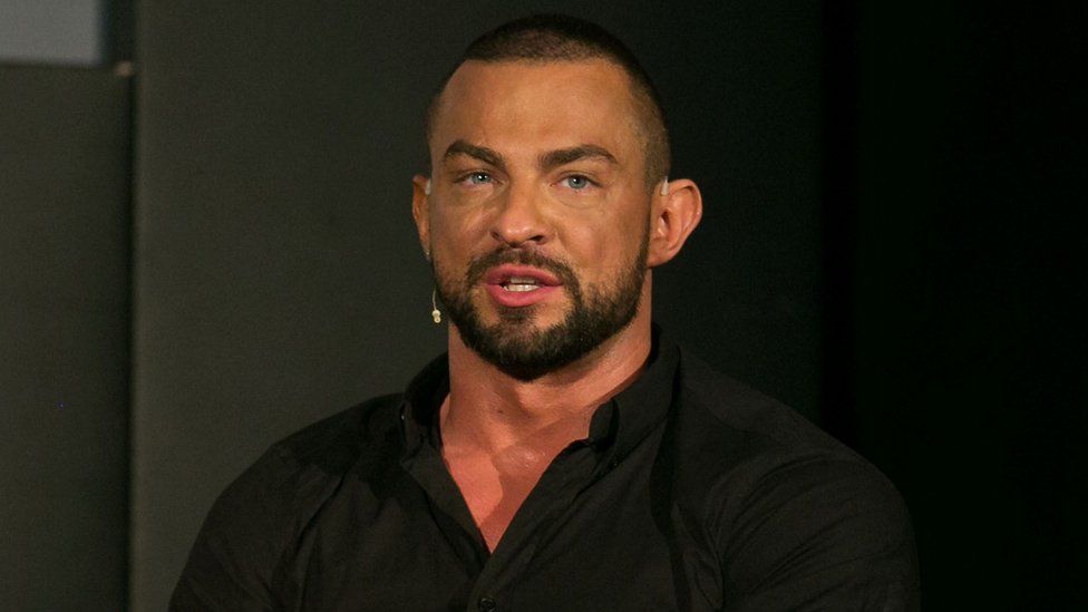 Robin Windsor wearing a black top. He is wearing a headset on his right ear and had a beard.