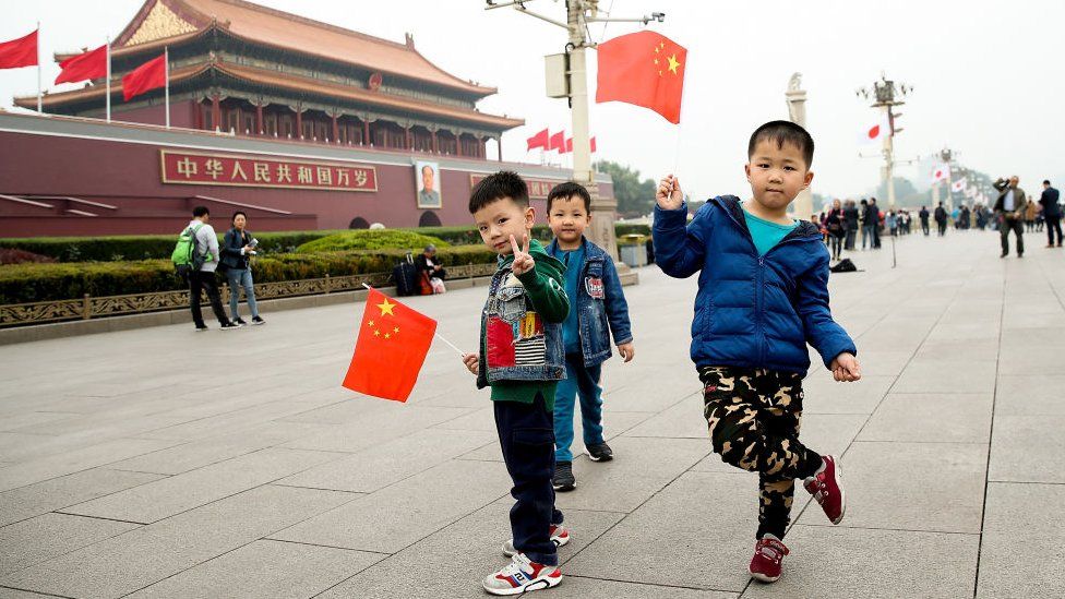 Young boys waves Chinese flags in front of the Tiananmen Gate on October 25, 2018