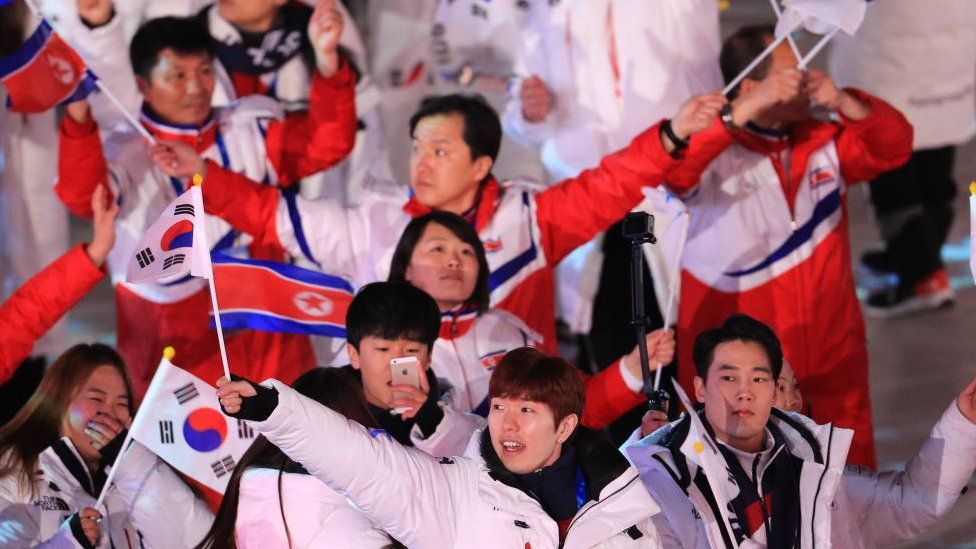 Delegations from North Korea and South Korea march under the Korean unification flag