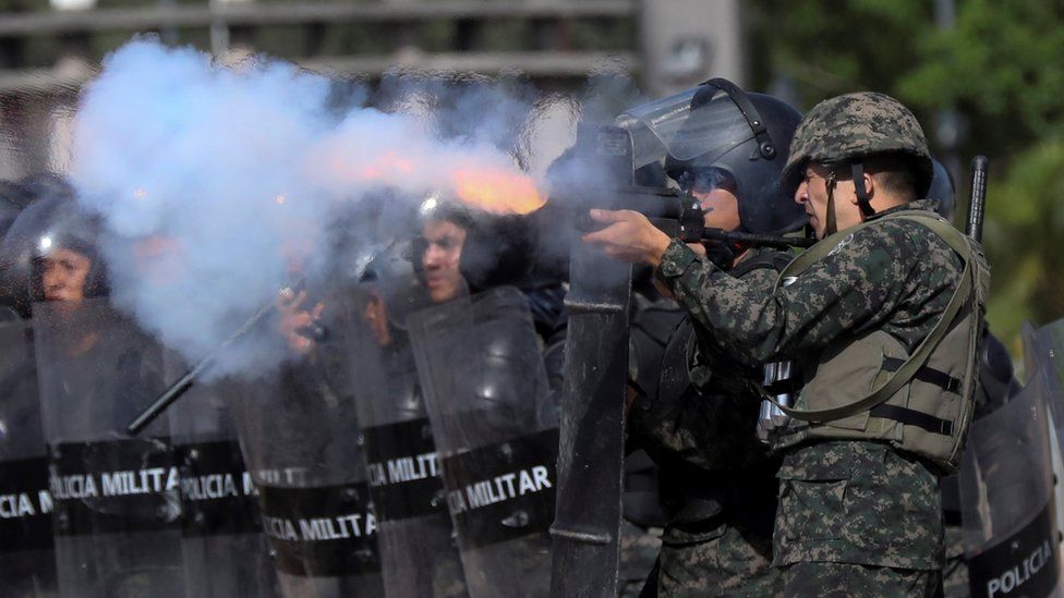Military police officers shoot tear gas at students during clashes, in Tegucigalpa